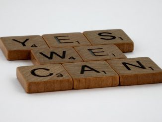Scrabble tiles spelling 'Yes We Can' on a white background, conveying encouragement.