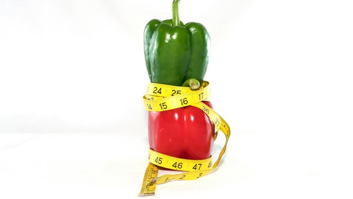 a red bell pepper wrapped in a measuring tape